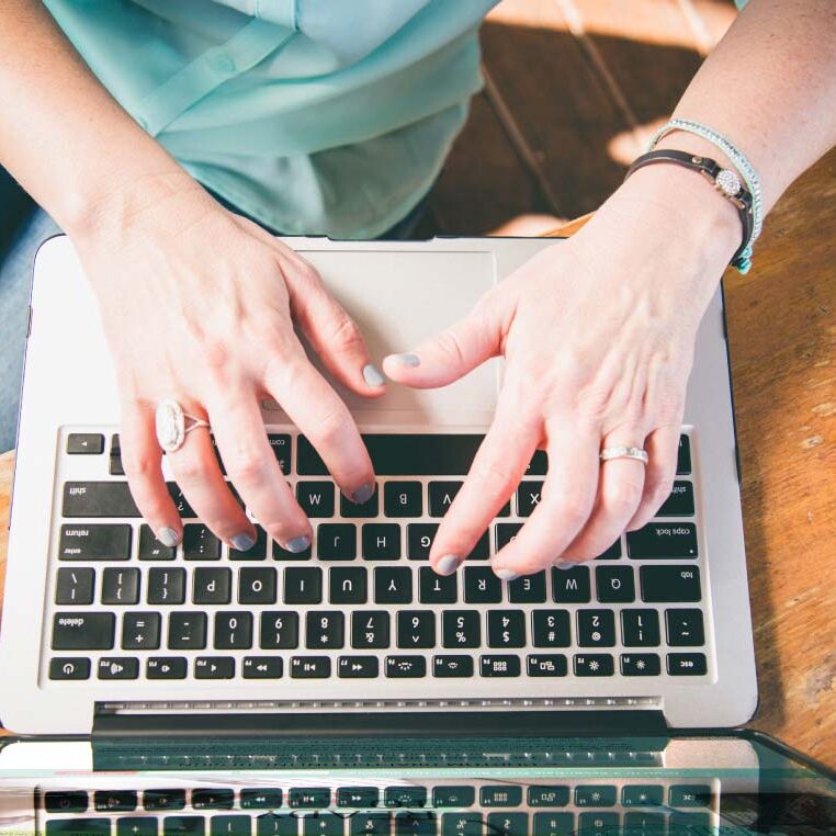 Janet's hand on Macbook, typing, answering questions, helping clients